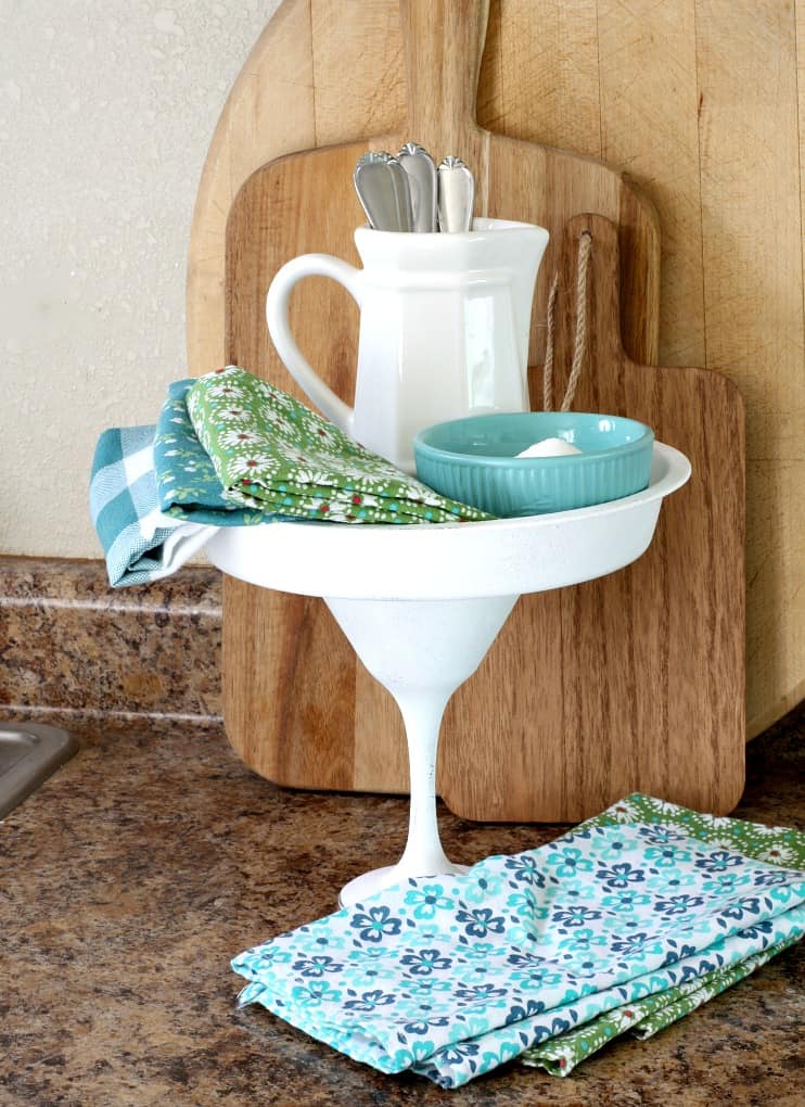 white cake plate with pitcher and bowl printed napkins and cutting boards in background