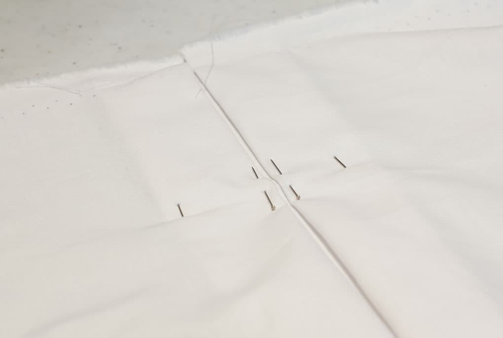 white fabric with pins inserted for box pleats