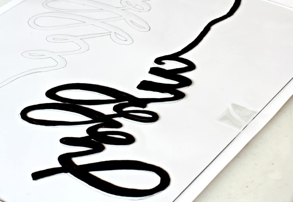 paper and glass sitting on table with lettering painted on the paper