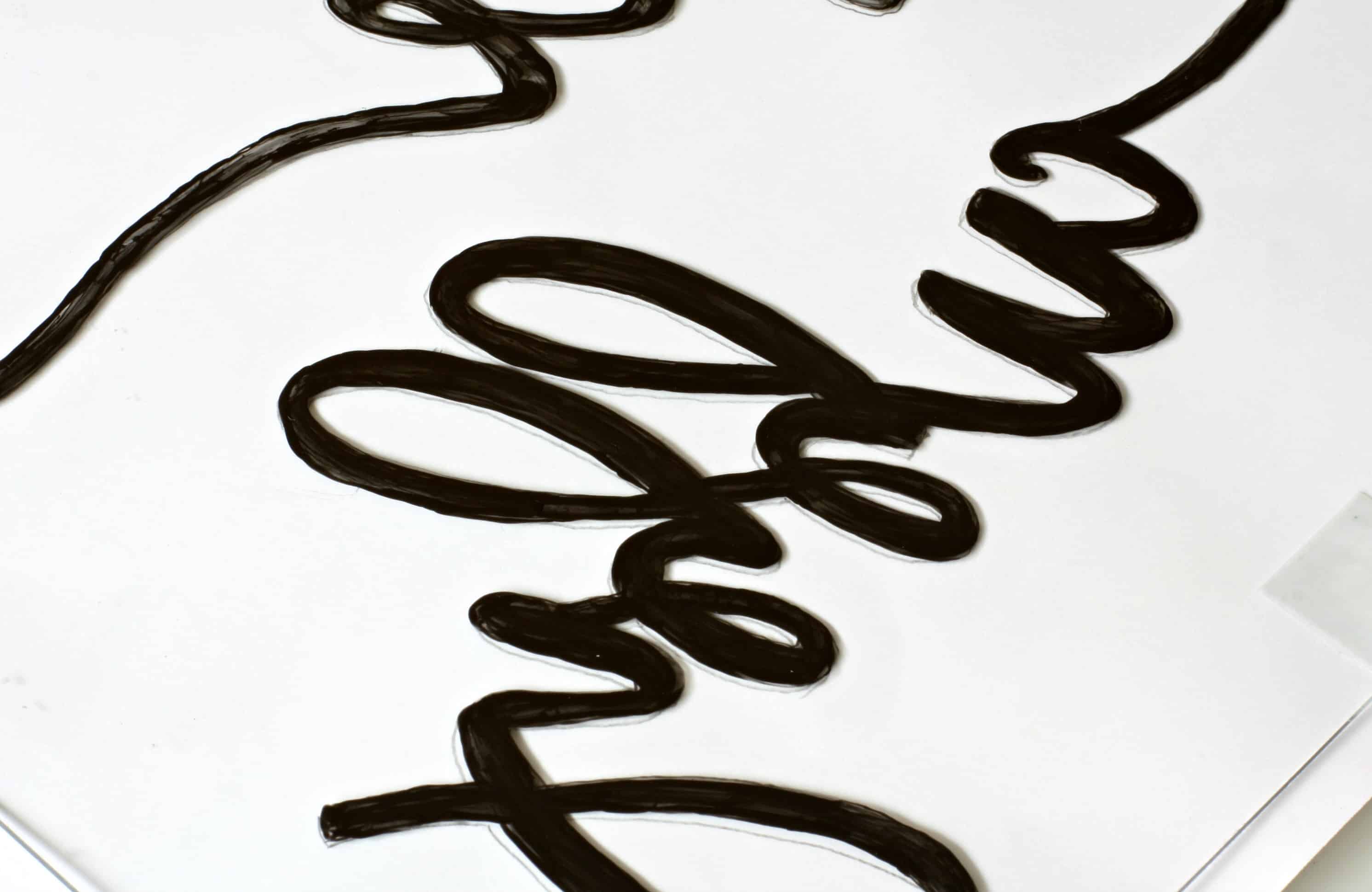 paper and glass sitting on table with lettering painted on the paper