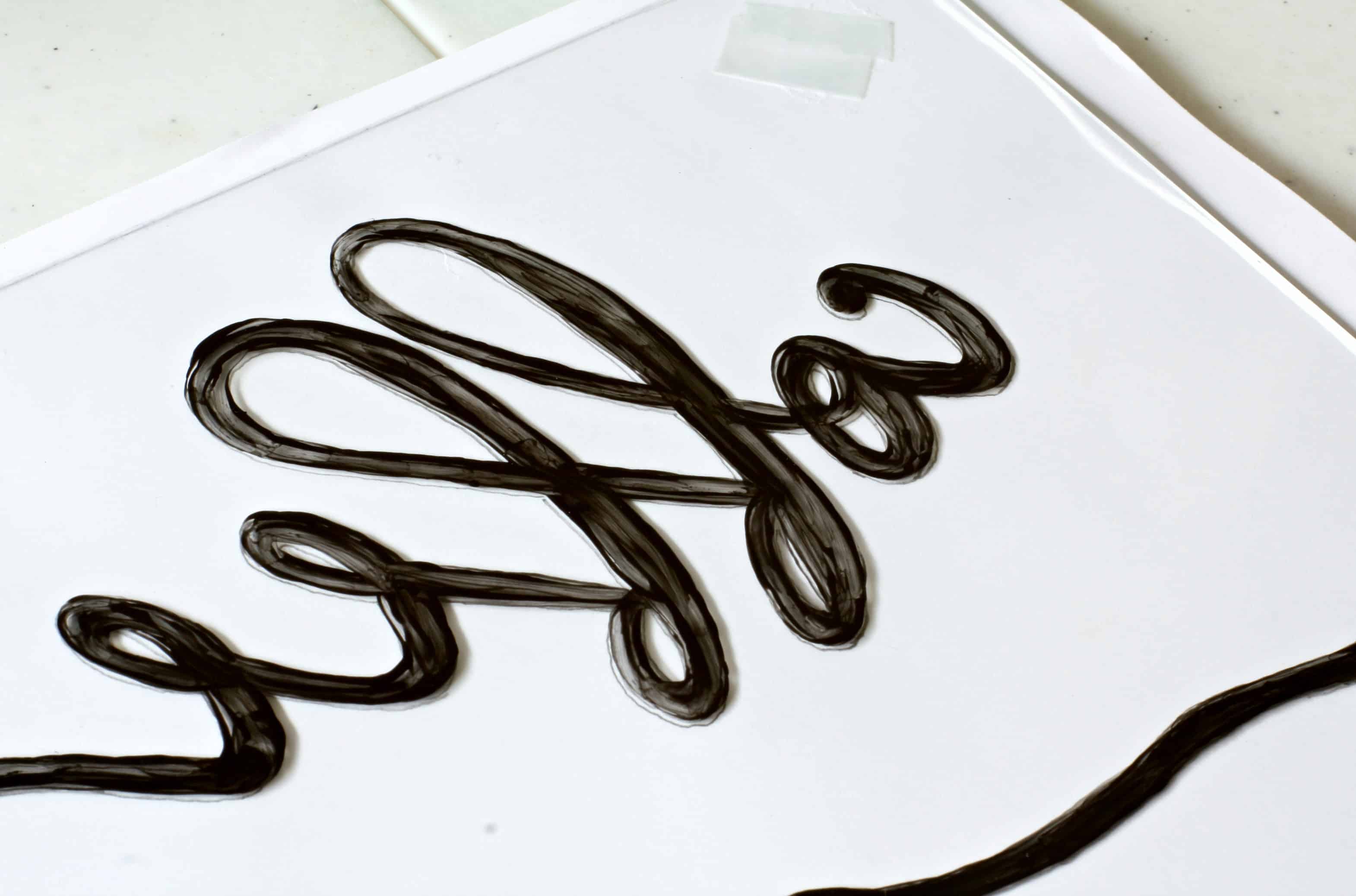 paper and glass sitting on table with lettering painted on the paper