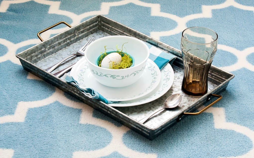 galvanized tray with dinner place setting and napkin with egg inside bowl on aqua and white rug