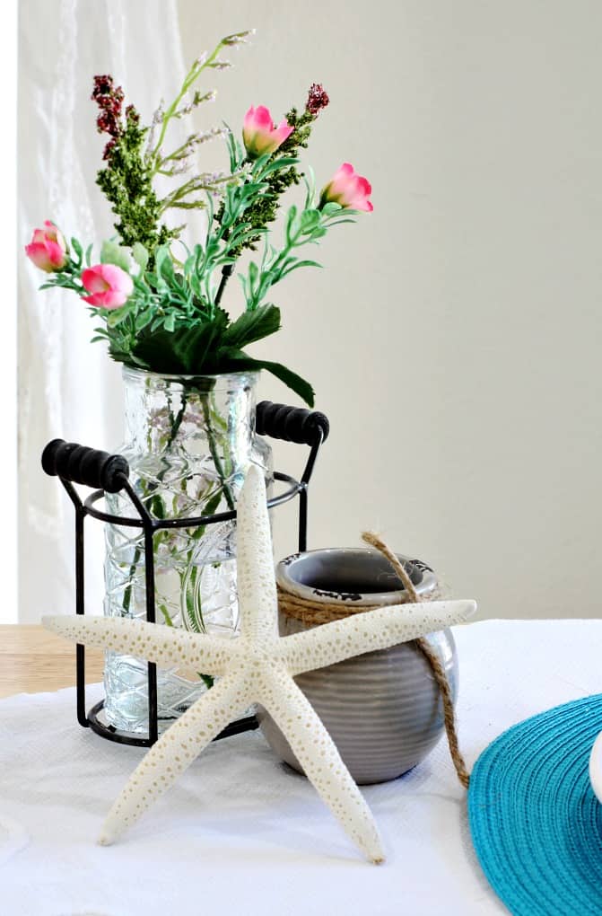 vase with flowers gray pot with starfish on counter with white tablecloth