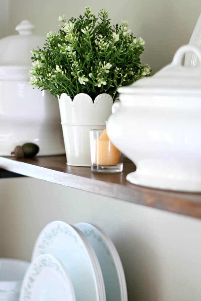 adding fall decor to a small kitchen open shelves with white dinnerware plants pumpkins and natural elements