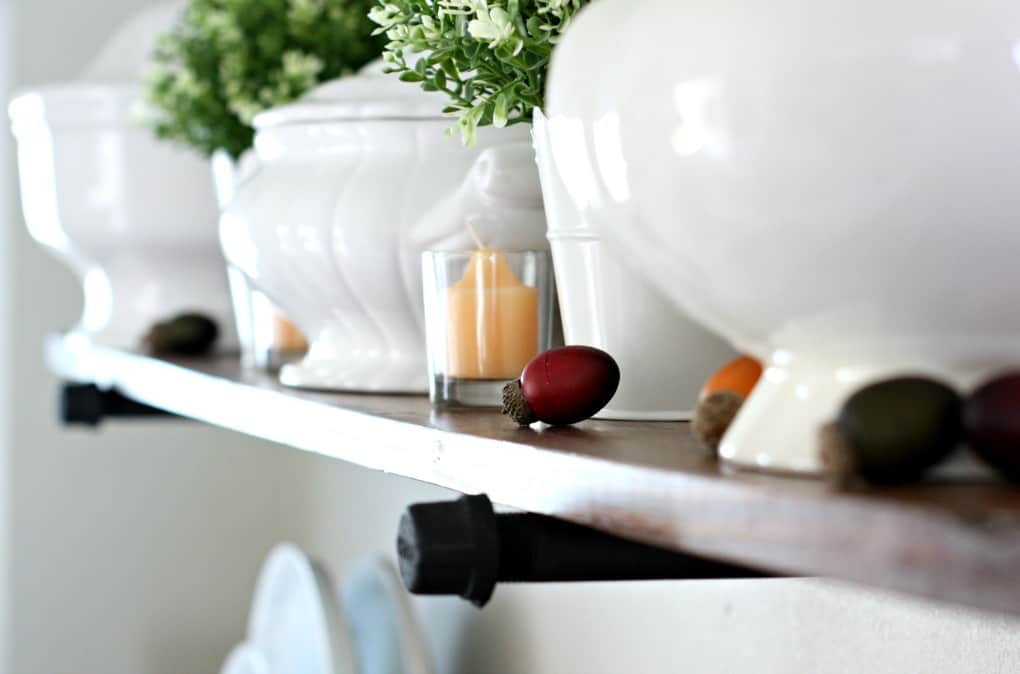 adding fall decor to a small kitchen open shelves with white dinnerware plants pumpkins and natural elements