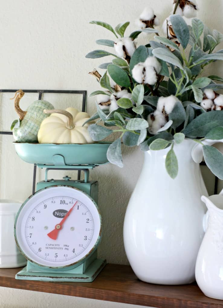 adding fall decor to a small kitchen open shelves with white dinnerware plants pumpkins and natural elements vintage scale cotton stems in pitcher