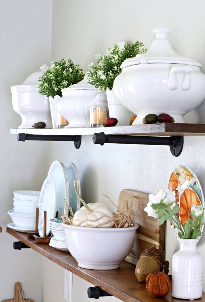 adding fall decor to a small kitchen open shelves with white dinnerware plants pumpkins and natural elements
