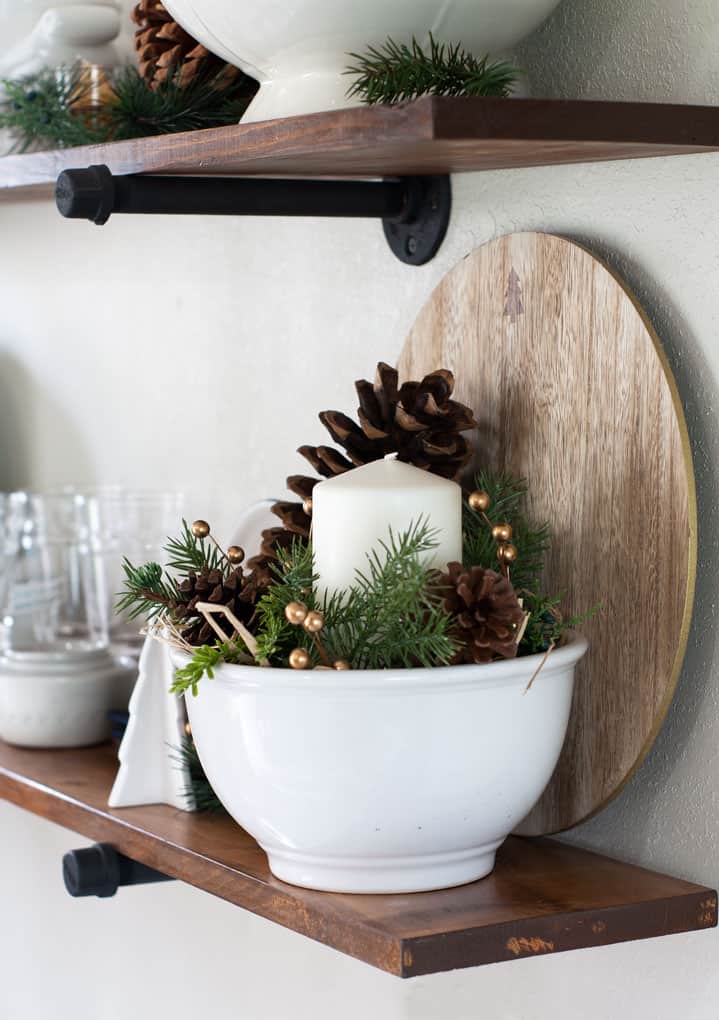 winter-valentine-decor-small-kitchen white dishes on open shelving in a kitchen with white bowl pine cones and candle