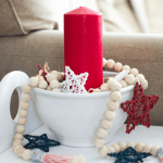 diy wood bead garland with stars white bowl with red candle and wood bead garland with red white blue stars on white table