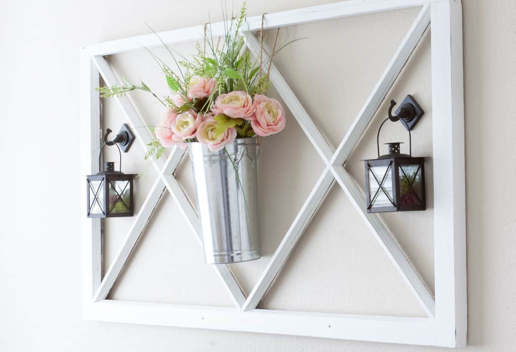 flowers in a pail window pane and lantern on wall