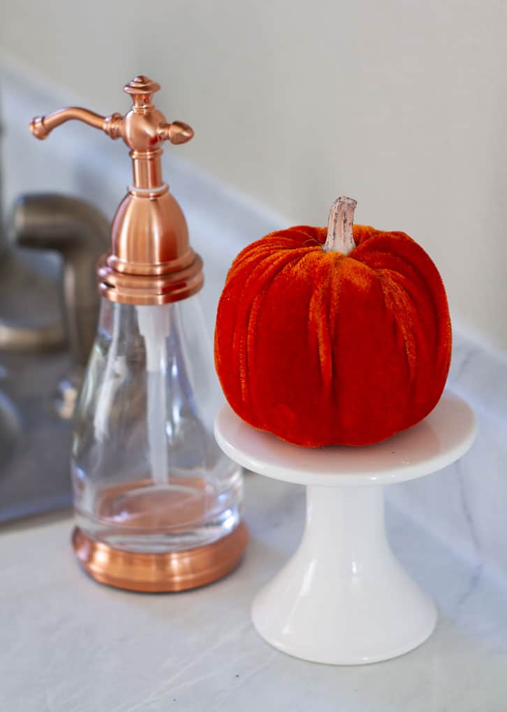 copper soap dispenser and velvet pumpkin on a cupcake plate