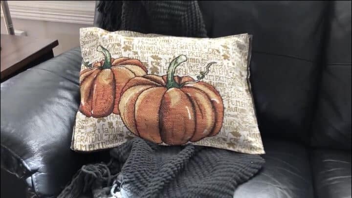 pumpkin pillow on leather chair with gray blanket