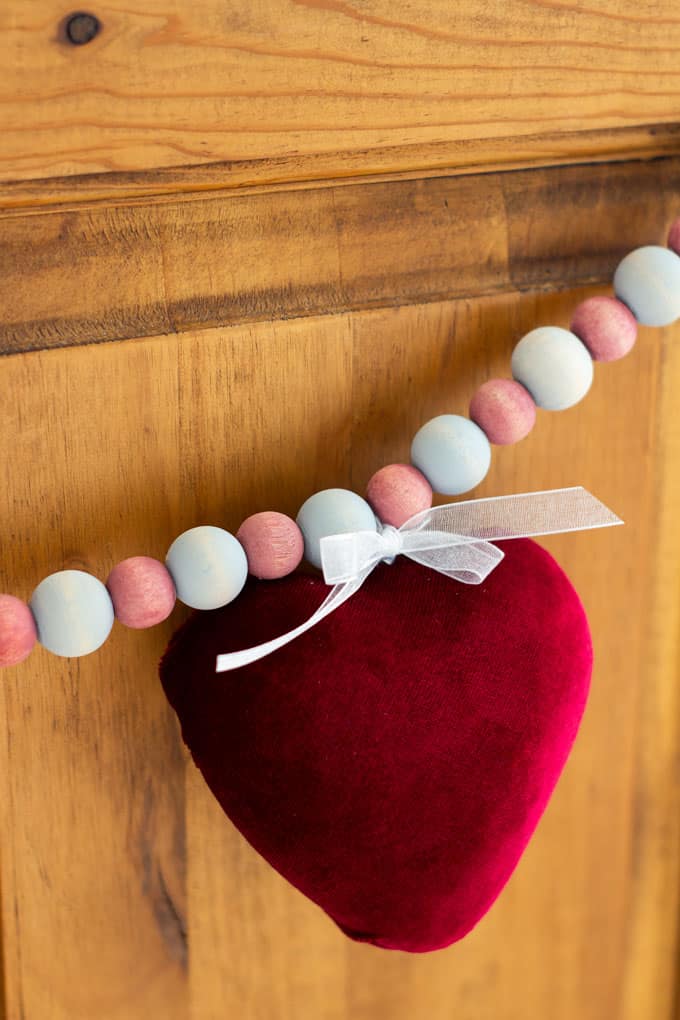 how to make a valentine garland with velvet covered hearts hanging on a wooden window bench