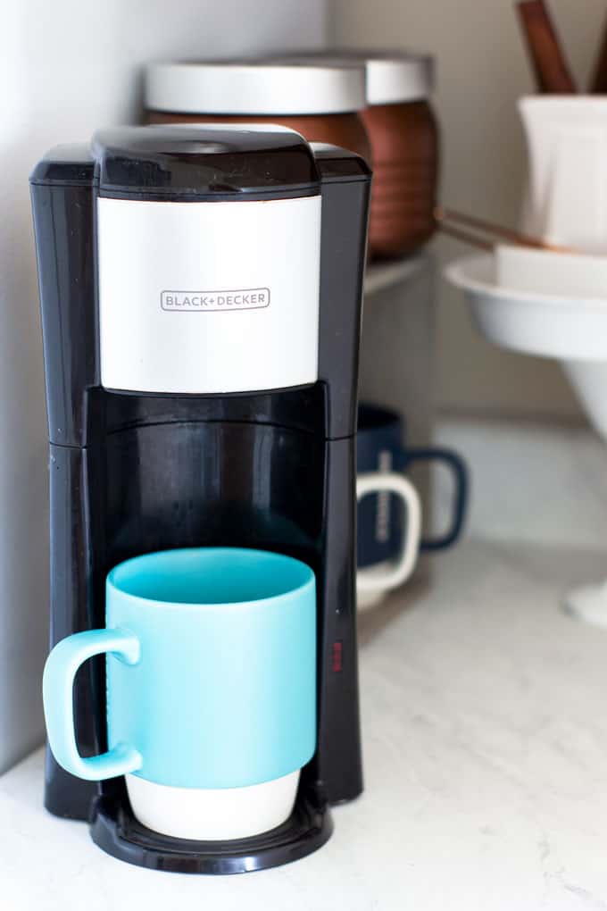 one cup coffee maker with green cup on counter