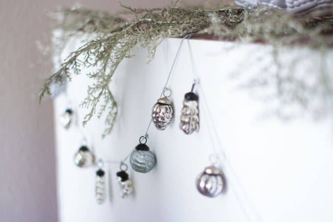 mercury glass ornament garland hanging on back of hutch with sparkly branches