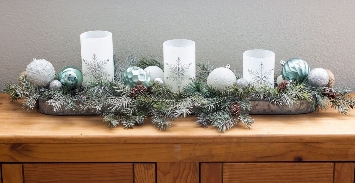 frosty christmas tiny home tour candles with greenery and ornaments on wood bench