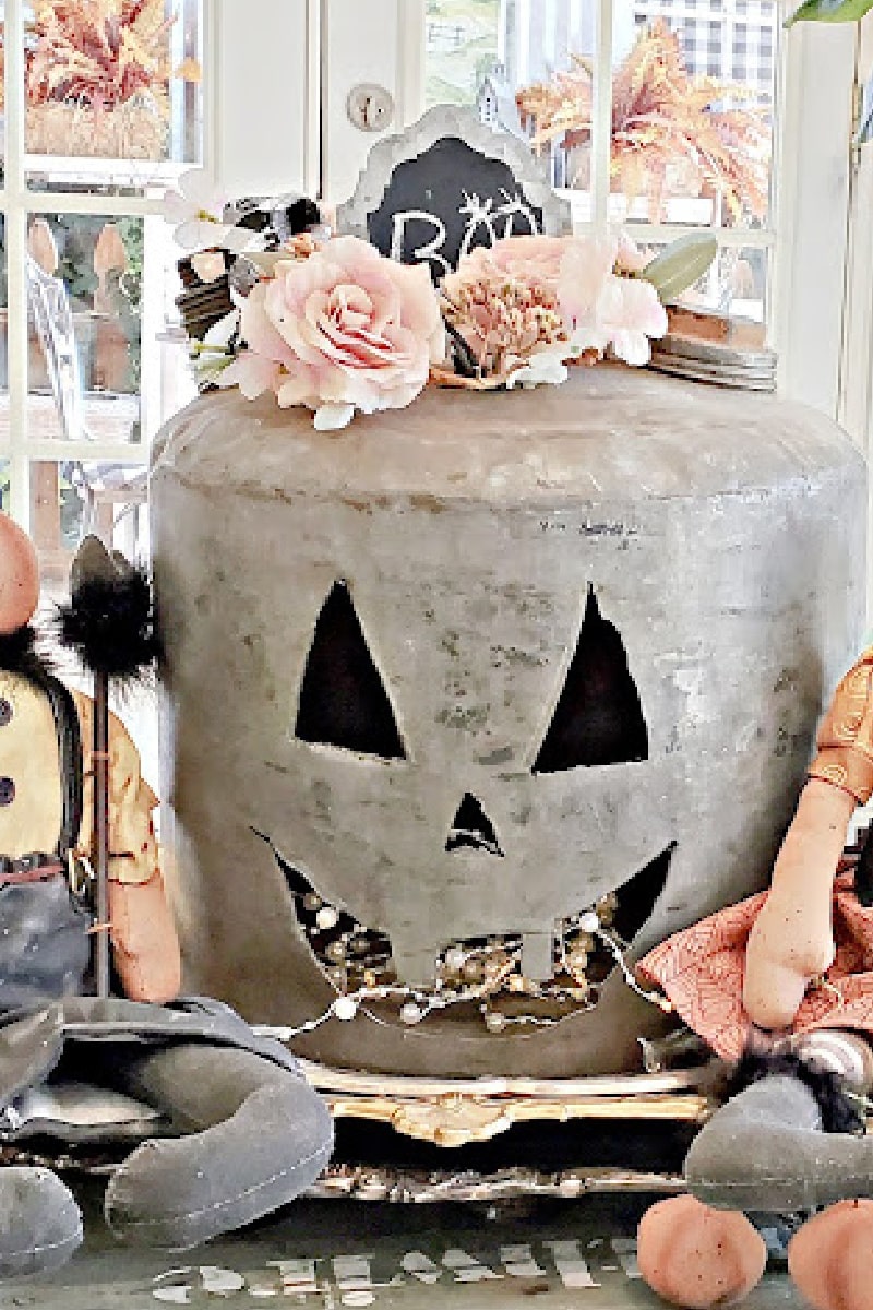 metal milk can disguised as a jack-o-lantern with cottage elements