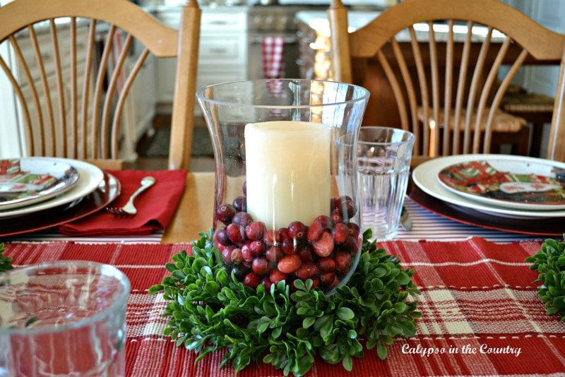 hurricane lamp with candle and cranberries and christmas greenery