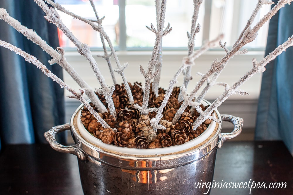 frosty branches in a silver urn with mini pine cones