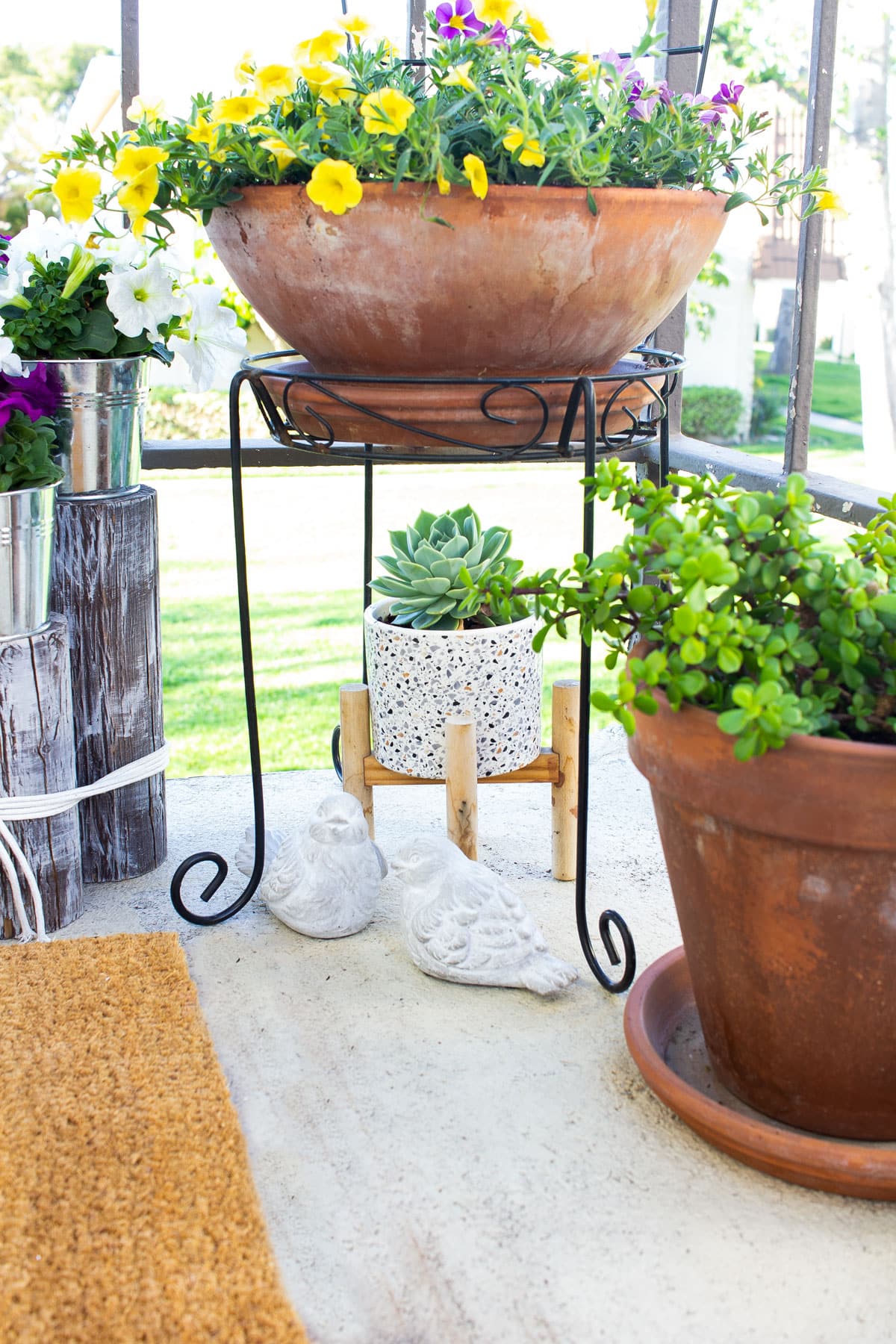 patio with spring florals and terra cotta pots plus cement birds and succulents