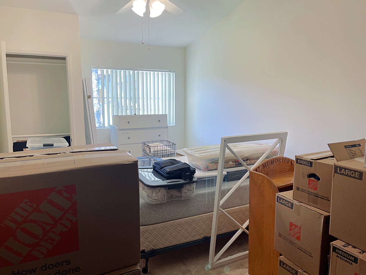 bedroom with moving boxes mess and furniture