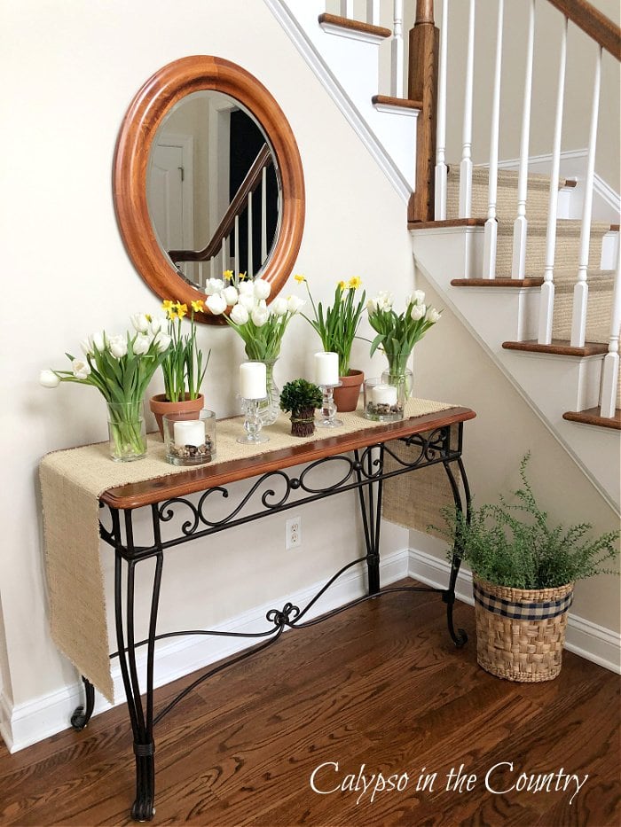entryway table with flowers in vases