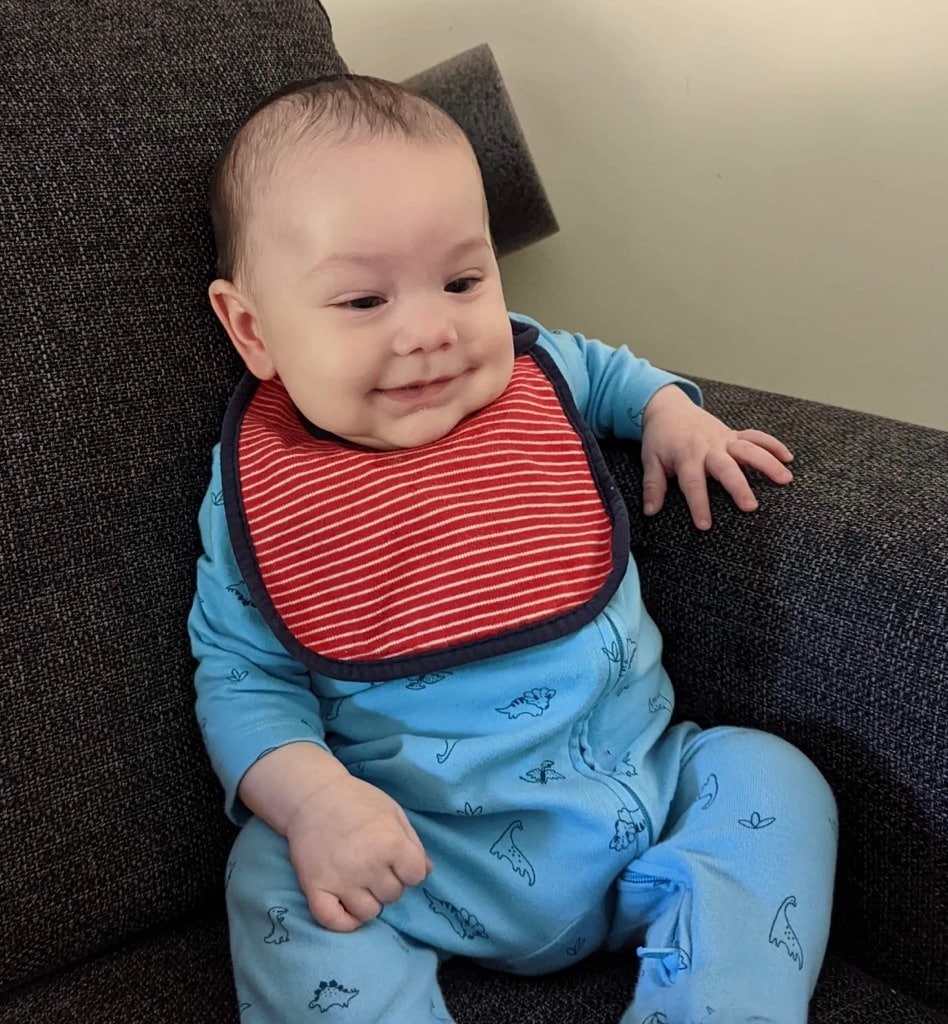 assemble boxed furniture baby sitting on sofa with smile on his face