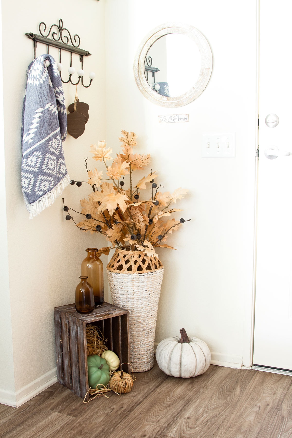 fall vignette in corner with woven vase crate with pumpkins and fall elements