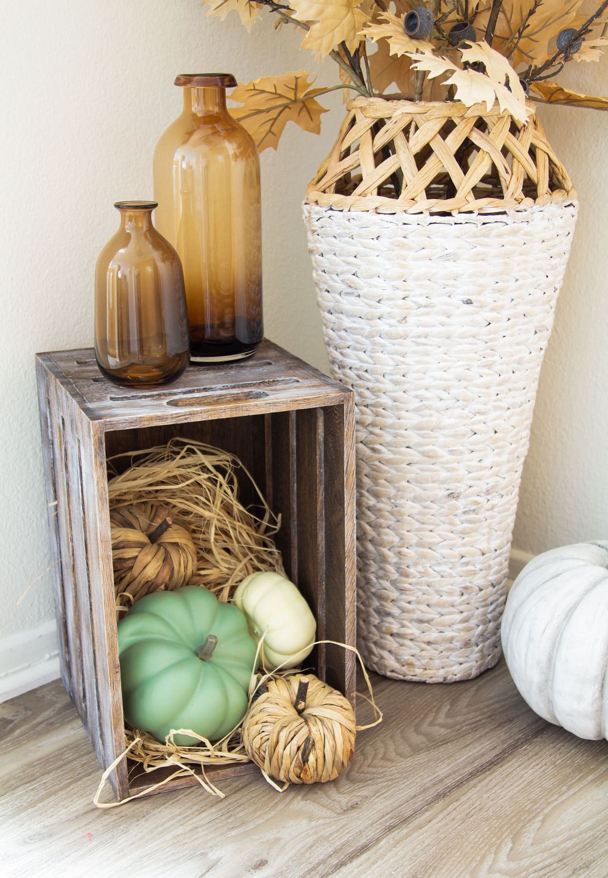 fall vignette in corner with woven vase crate with pumpkins and fall elements