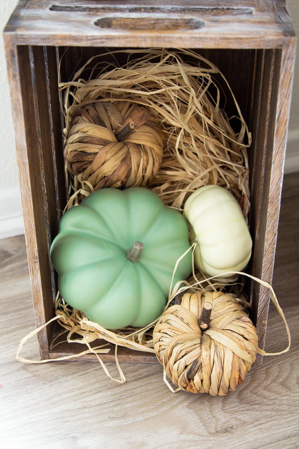 crate with green pumpkin and woven pumpkins and grass