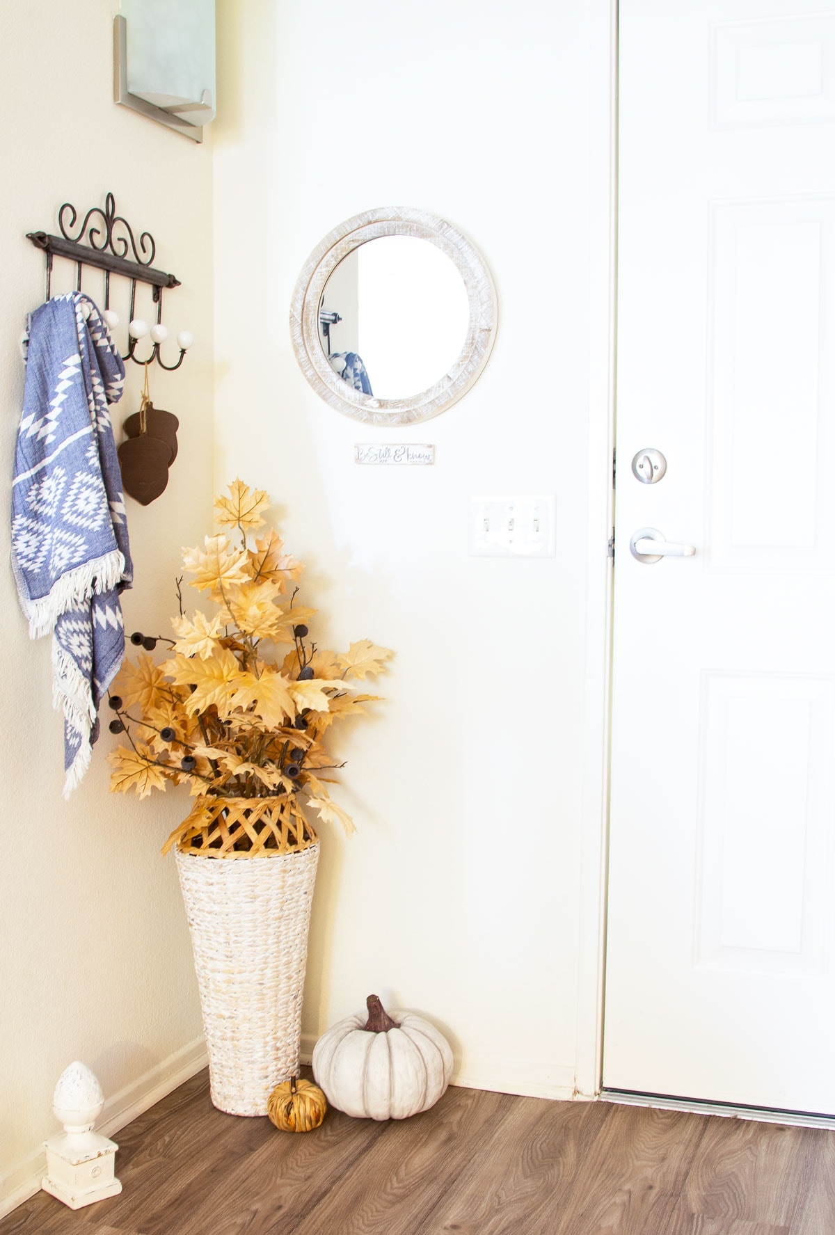 small apartment fall living room tour entryway with floor vase and fall foliage white pumpkin and coat hanger with blue throw