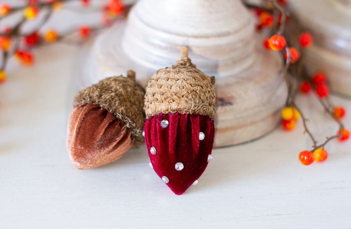 two velvet acorns with real cups in red and chocolate colors the red one has rhinestones