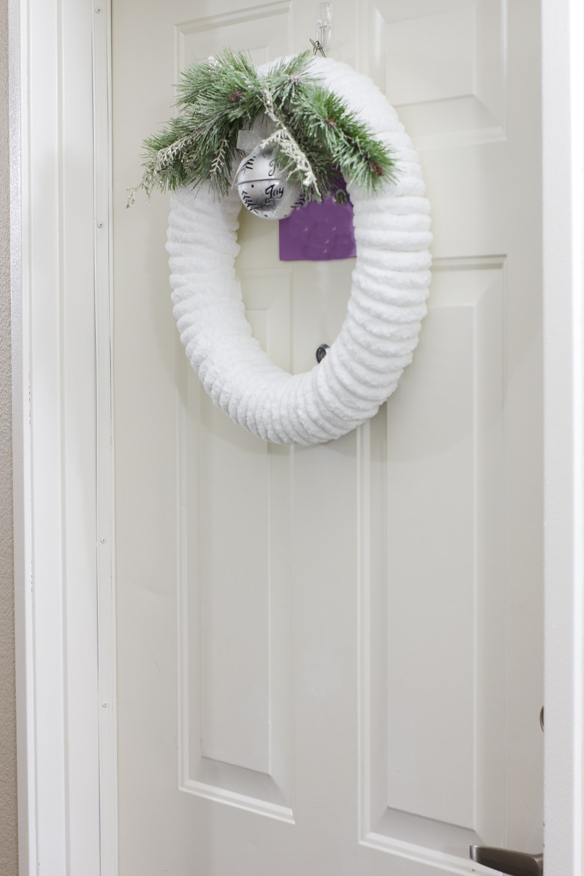 diy plush chunky yarn christmas wreath hung on apartment door