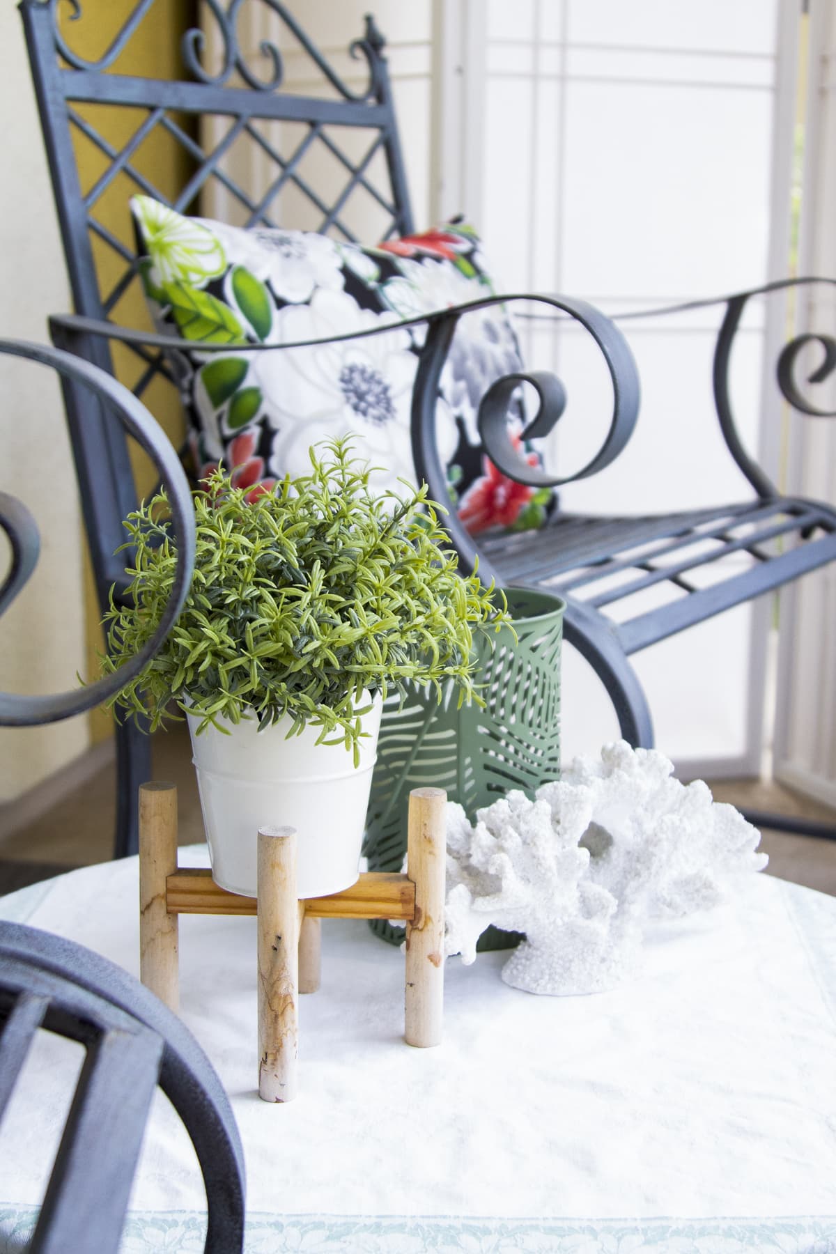 apartment balcony container gardening for summer plant in white container on stand with coral and candle holder