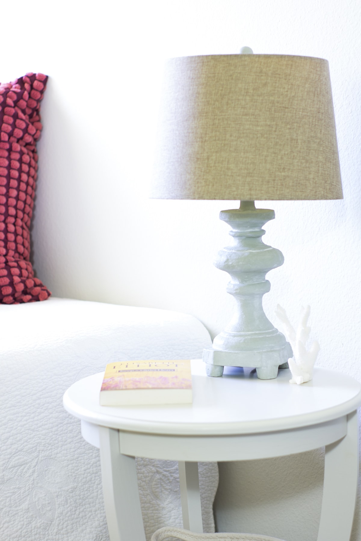 lamp on nightstand with bed and pink pillows to the left