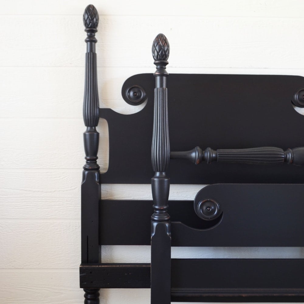 black bedframe leaning against wall