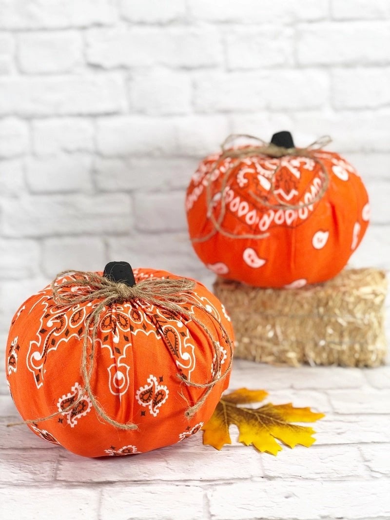 faux pumpkins wrapped in orange bandanas and twine on brick surface