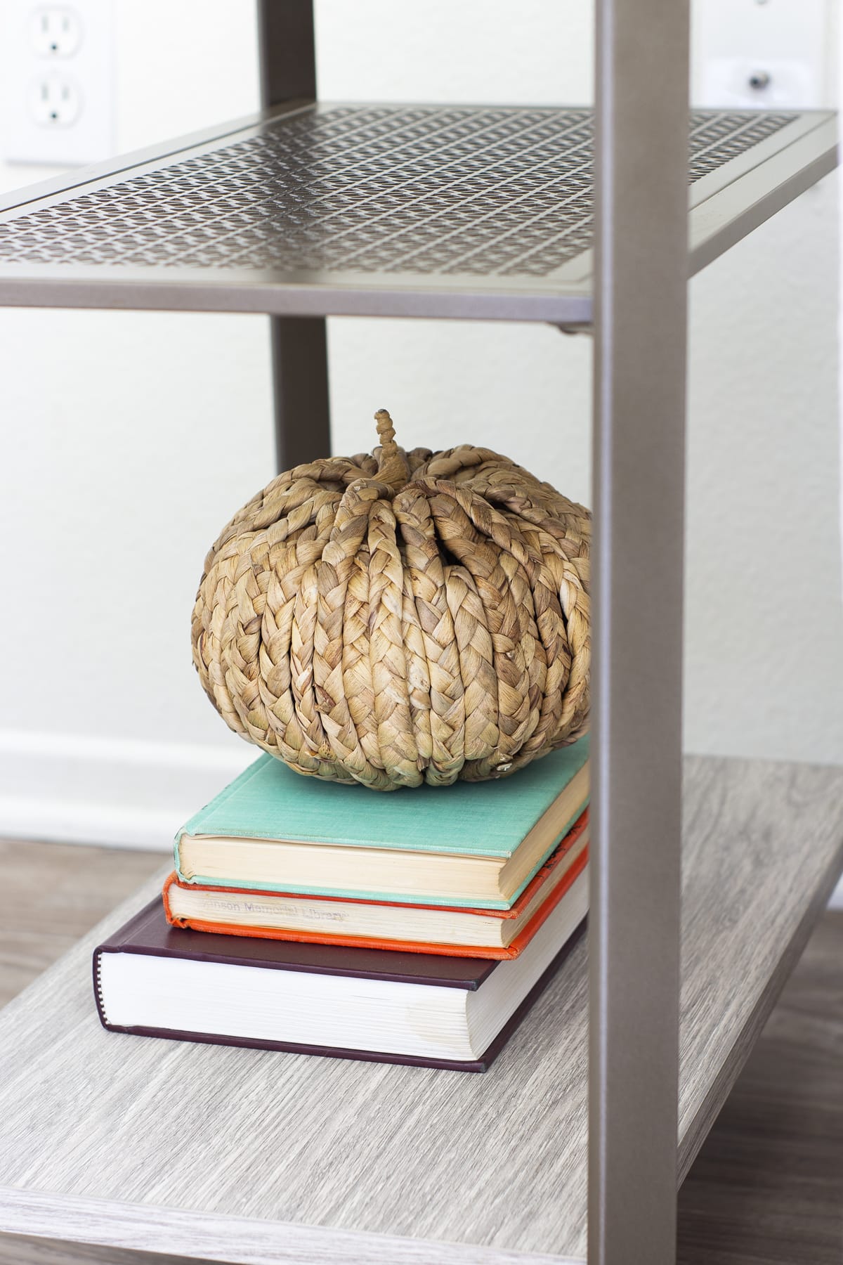 woven pumpkin sitting on top of a stack of books on table