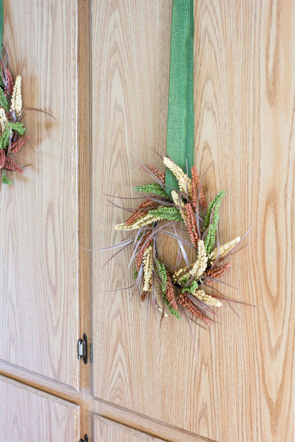fall wreath with green ribbon on cabinet door