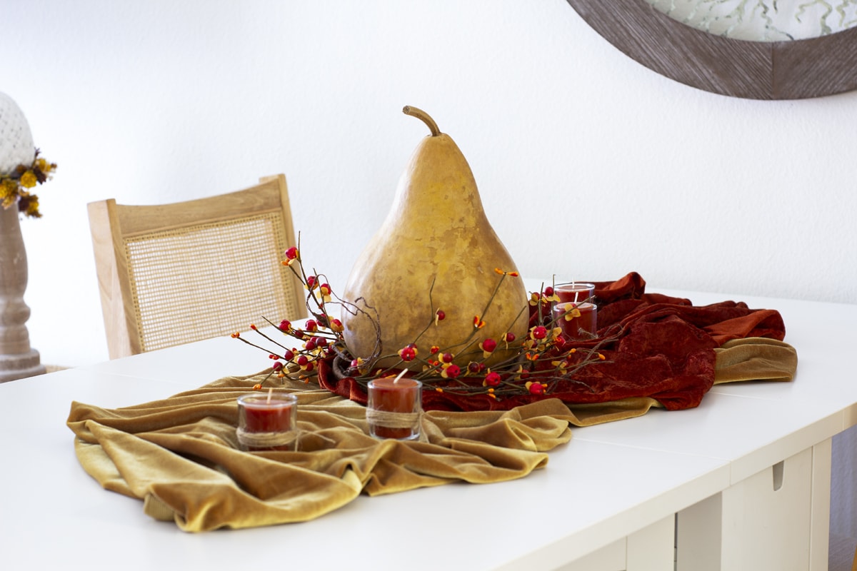 how to decorate your cozy apartment with fall faux florals fall centerpiece with large gourd on white table