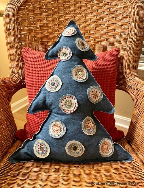 christmas tree pillow with soft ornaments on straw chair