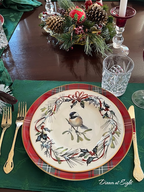 winter tablescape with bird on plate and dinnerware on green mat
